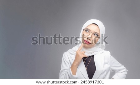 Portrait of Muslim woman in office attire and wearing a hijab. Corporate  or business people concept. Isolated on grey background. 16:9 ratio with copyspace on one side of the banner Royalty-Free Stock Photo #2458917301