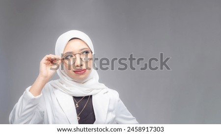 Portrait of Muslim woman in office attire and wearing a hijab. Corporate  or business people concept. Isolated on grey background. 16:9 ratio with copyspace on one side of the banner Royalty-Free Stock Photo #2458917303