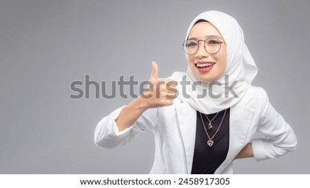 Portrait of Muslim woman in office attire and wearing a hijab. Corporate  or business people concept. Isolated on grey background. 16:9 ratio with copyspace on one side of the banner Royalty-Free Stock Photo #2458917305