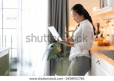 attractive smart asian adult female wear casual cloth working form home using laptop smartphone device,asian female woman work in kitchen island home studio office online hand use smartphone at home