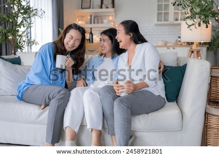 Asian woman friend group mature women meeting and sharing personal stories laughing at home while drinking coffee woman energetic women meeting and sharing personal stories in a living room warm house Royalty-Free Stock Photo #2458921801