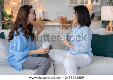 Asian woman friend group mature women meeting and sharing personal stories laughing at home while drinking coffee woman energetic women meeting and sharing personal stories in a living room warm house Royalty-Free Stock Photo #2458921809