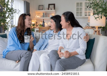 Asian woman friend group mature women meeting and sharing personal stories laughing at home while drinking coffee woman energetic women meeting and sharing personal stories in a living room warm house Royalty-Free Stock Photo #2458921811