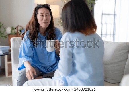 Asian woman friend group mature women meeting and sharing personal stories laughing at home while drinking coffee woman energetic women meeting and sharing personal stories in a living room warm house Royalty-Free Stock Photo #2458921821