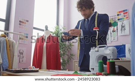 Handsome hispanic man photographing fashion designs in a tailor shop.