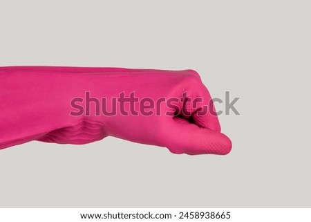 Closeup of woman hand wearing pink rubber glove greeting someone with fist bump gesture. Indoor studio shot isolated on gray background.