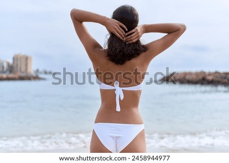 Young african american woman wearing bikini combing hair at beach