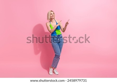 Full size photo of cute woman wear colorful top jeans look directing at logo empty space arms folded isolated on pink color background