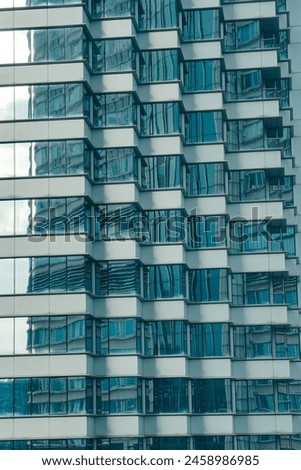 The image shows a modern glass skyscraper with a blueish reflection. Royalty-Free Stock Photo #2458986985