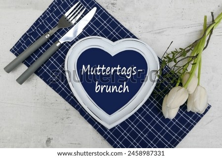 Mother's Day breakfast concept. Decoration for Mother's Day brunch with white tulips, cutlery and the text Mother's Day Brunch. German inscription translated means Mother's Day Brunch.