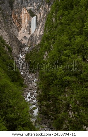 Boka waterfall in Slovenia, near Bovec. Easy trekking nature trail in the forest with the view of the immense waterfall overhanging the mountains visible from the road, long exposure photography.