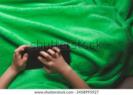 Phone in hands of child. Little boy playing mobile games on smartphone. Hand closeup.