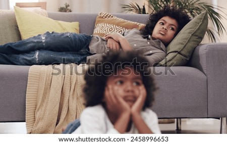 Watching tv, child and couch in living room while bored, relaxing and resting on school holiday. Young boy, laying and comfort on sofa for cartoons, series and streaming for vacation with family Royalty-Free Stock Photo #2458996653