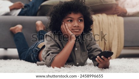 Watching tv, child and carpet in living room with remote, relaxing and resting on school holiday. Young boy, laying and browsing videos for cartoons, series and streaming for vacation with family
