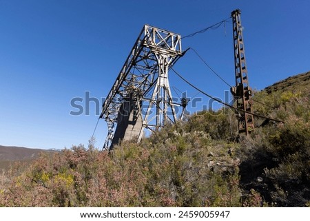 Abandoned industrial coal mining steel structure tower from cableway with cable in Tormaleo Asturias province of Spain on a bright sunny day. Royalty-Free Stock Photo #2459005947