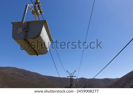 Abandoned industrial coal mining cart on cableway with rusty metal tower with cable on a bright sunny spring day with flower meadow and blue sky Royalty-Free Stock Photo #2459008277