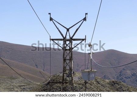 Abandoned industrial coal mining cart on cableway with rusty metal tower with cable on a bright sunny spring day with flower meadow and blue sky Royalty-Free Stock Photo #2459008291