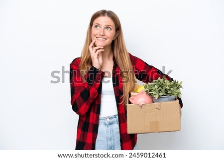 Young caucasian woman making a move while picking up a box full of things isolated on white background thinking an idea while looking up