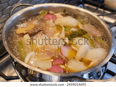 Chicken stock boiling in a pot set upon a stove