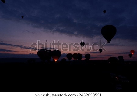 Feel the freezing while waiting for sunrise in hot balloons before dawn to drive out to scenic viewpoints, and colorful ball gowns, and snap photos with fairy chimneys in the winter Cappadocia, Turkey Royalty-Free Stock Photo #2459058531