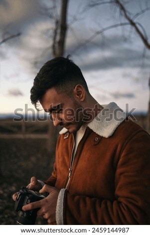 Close-up of photographer looking at the photos of a beautiful landscape in the countryside on his camera.