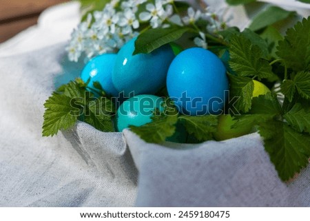 Unique, vibrant blue and green Easter eggs nestled together in a white bag.