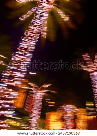 Palm trees wrapped in colorful Christmas lights are seen in this slow-shutter exposure. Photographed against the night sky.