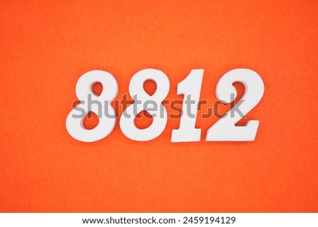 The number 8812 is made from white painted wood placed on a background of orange paper.