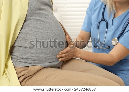 Pregnancy checkup. Doctor examining patient's tummy in clinic, closeup