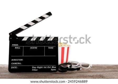 Movie clapper, bucket of tasty popcorn, glasses and film reel on wooden table against white background, space for text