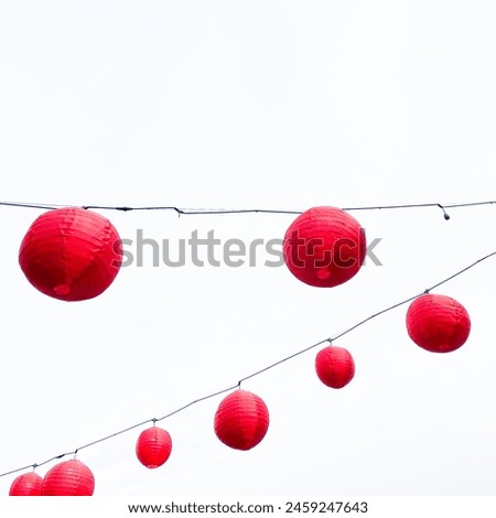 Picture of red lantern tied in black cable with white background