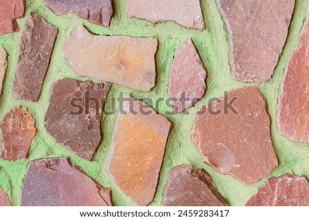 It is photo of colorful stones on green background. Its close up of multicolored stone wall of building. It is the photo of mosaic tile floor. It's view of wall texture.