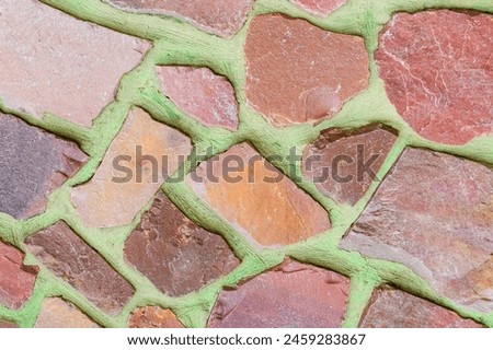It is photo of colorful stones on green background. Its close up of multicolored stone wall of building. It is photo of mosaic tile floor. It's view of wall texture.