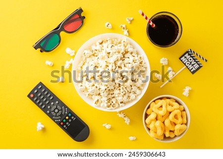 Enjoy ultimate movie night in. Top-view of savory snacks, 3D glasses, remote for streaming. Movie-themed decoration on stick add festive touch on yellow backdrop. Perfect for any home cinema setup