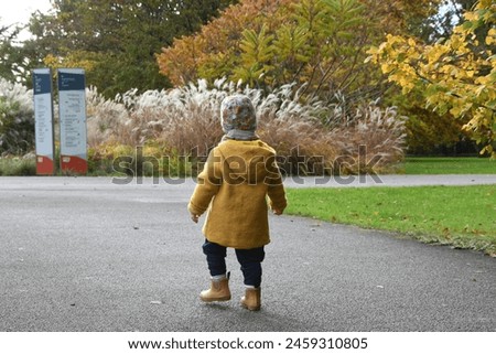 Autumn Bliss: Toddler in Yellow - Experience the charm of autumn with this high-resolution image featuring a young toddler joyfully walking in a park, dressed in bright yellow jacket.