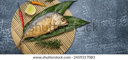 Fried Mackerel Delicious sea fish with lime and fresh chilli on a bamboo mat. Top view on gray background