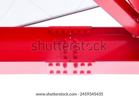 Large red screw hexagon flange nut supporting structures, metal frame of prefabricated building on white background. Large metal posts or structure are painted of outdoor billboard construction work. Royalty-Free Stock Photo #2459345435