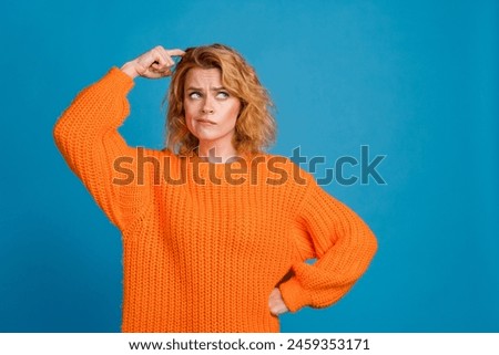 Photo of minded lovely woman wear trendy orange clothes look empty space isolated on blue color background
