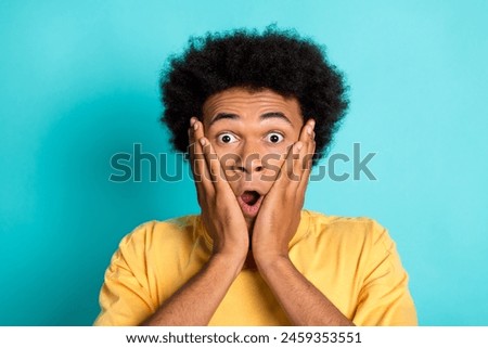 Photo of astonished guy with afro hair dressed yellow t-shirt palms cheekbones staring at discount isolated on turquoise color background
