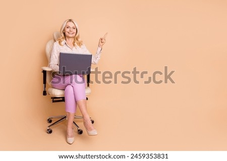 Full body photo of nice retired female sit armchair netbook point empty space wear trendy formalwear isolated on beige color background