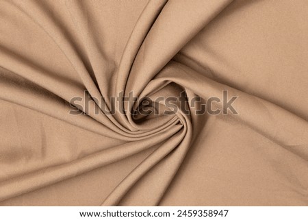 Swirled khaki-colored fabric texture background. This fabric is made of polyester and spandex. Royalty-Free Stock Photo #2459358947