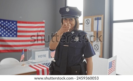 Hispanic policewoman pointing at camera in voting center with american flags Royalty-Free Stock Photo #2459360053