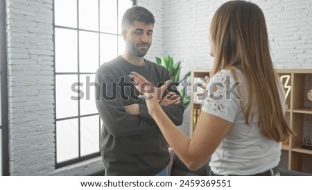 A couple is having a discussion in a brightly lit home's living room, conveying tension between man and woman. Royalty-Free Stock Photo #2459369551