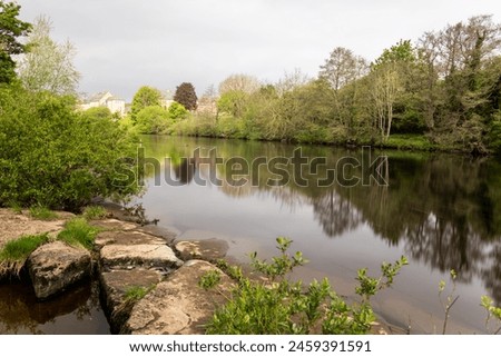 The River Tees, landscape with a reflection of the trees, houses further down the river can just be seen. This image is a long exposure. Royalty-Free Stock Photo #2459391591