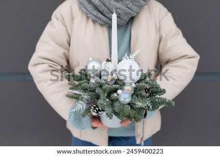 Person Holding Christmas Arrangement, holiday decorations and colors.