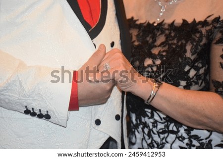 Holding hand in wedding attire, diamond ring, gold ring, black and white wedding dress, white suit with black button red tie wedding day pictures formal wear