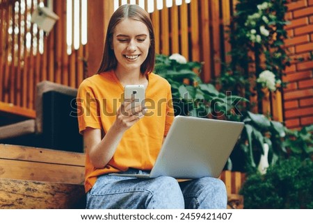 Skilled female blogger with smile on face using smartphone for chatting with followers and enjoying time at cozy cafeteria, cheerful woman happy from reading good news in social network on cellular