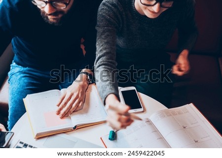Young clever students watching webinar online while browsing internet and resting in university campus connected to wifi, concentrated colleagues using netbook for searching information and studying Royalty-Free Stock Photo #2459422045