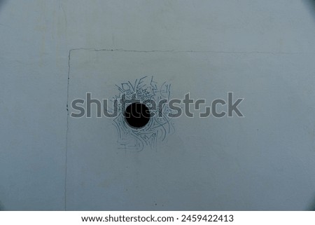closeup of a round hole on white wall with green color linear pattern