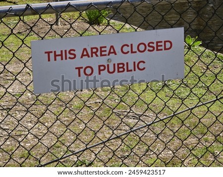 A sign that says this area closed to public attached to a fence.